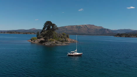 AERIAL---Sailboat-on-beautiful-Hermoso-Lake,-Neuquen,-Argentina,-spinning-shot