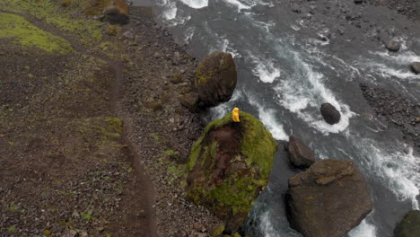 Luftaufnahme:-Von-Oben-Nach-Unten-Aufnahme-Eines-Mannes,-Der-Auf-Einem-Felsen-In-Der-Nähe-Eines-Flusses-Steht