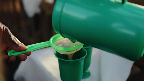 Traditional-Ugandan-banana-beer-poured-through-sieve-into-cups