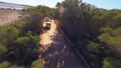 FPV-aerial-flying-past-a-VW-minibus-driving-along-a-scenic-coastal-highway