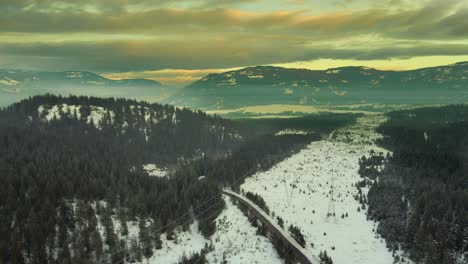 Spektakulärer-Sonnenuntergang-über-Schneebedeckten-Bergen:-Luftaufnahmen-Von-Stromleitungen