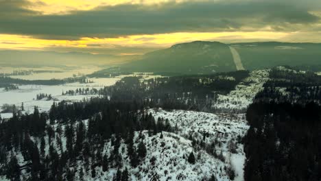 Atemberaubende-Luftaufnahme-Von-Stromleitungen-In-Verschneiter-Berglandschaft-Bei-Sonnenuntergang
