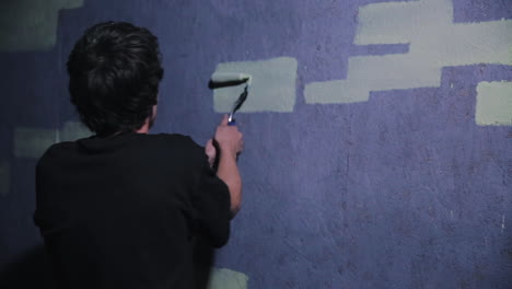 A-graffiti-artist-steadily-touches-up-a-brick-with-a-paint-roller-to-form-graffiti
