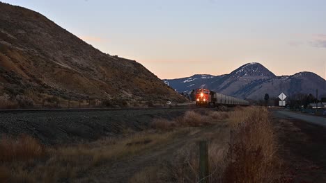 Güterzug,-Der-In-Der-Abenddämmerung-Auf-Der-Eisenbahn-In-Kamloops-Unterwegs-Ist,-Mit-Mount-Paul-Im-Hintergrund