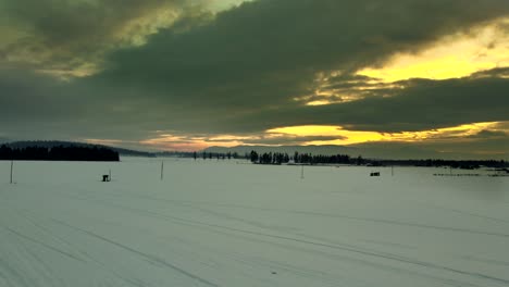 Snowcovered-field-during-sunset,-an-aerial-shot-with-a-dramatic-sky-close-to-Enderby-in-British-Columbia