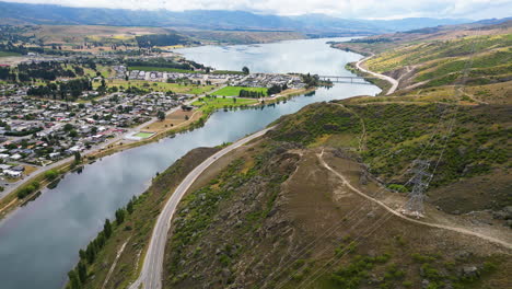Luftdrone-Rückwärts-Bewegende-Aufnahme-über-Der-Stadt-Cromwell-Am-Dunstan-Lake-In-Neuseeland-Mit-Blick-Auf-Eine-Kurvenreiche-Straße,-Die-Durch-Das-Hügelige-Gelände-Führt