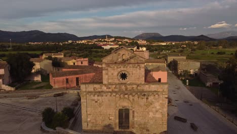 Front-exterior-facade-of-Tratalias-old-historical-church-in-South-Sardinia,-aerial