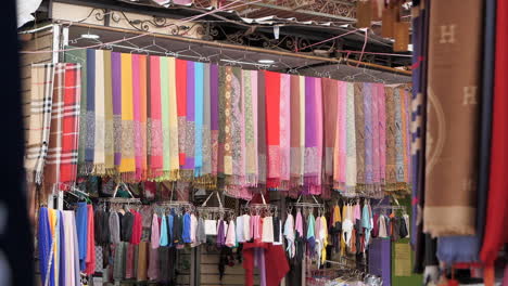 Colorful-textiles-on-hangers-for-sale-in-Marrakesh-medina,-Morocco