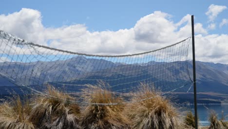 Volleyball-net-waving-in-a-fresh-alpine-breeze-in-front-of-bushes-and-mountain-range