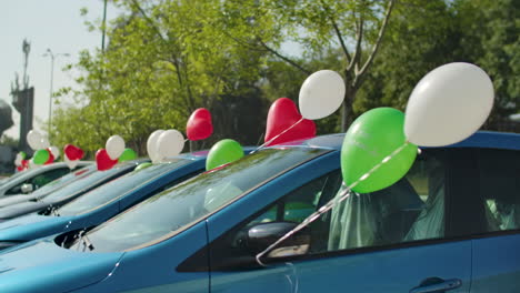 A-row-of-cars-decorated-with-helium-filled-multi-colored-ballons,-for-a-party-or-a-wedding