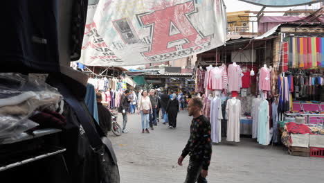 Dolly-shot-across-Medina-colourful-outdoor-market-stalls-selling-clothing-and-handmade-fabric
