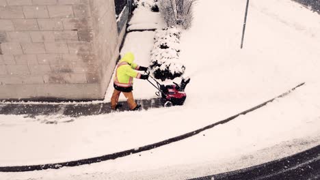 Unrecognisable-operator-using-snowblower-to-clean-driveway-when-snowing,-Brampton,-Ontario,-Canada
