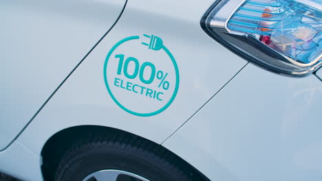 White-Electric-Car-With-100%-Electric-Sticker-On-Exterior-Side-Surface
