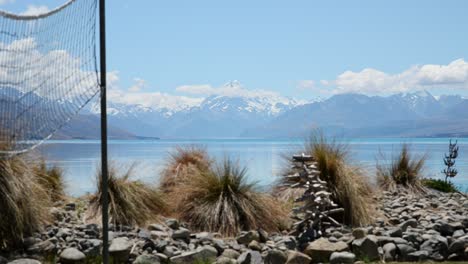 Büsche-Und-Ein-Volleyballnetz-Mit-Verschneitem-Mount-Cook-Und-Blauem-Lake-Pukaki-Im-Hintergrund