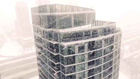 Modern-apartment-building-in-Toronto-during-heavy-blizzard,-aerial-drone-view