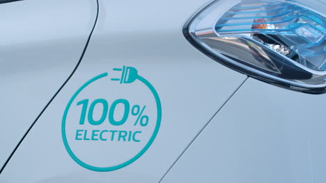 The-text-100-percent-electric-on-the-white-metal-sheet-of-a-car