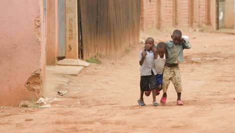 Slow-motion-long-shot-of-three-boys-walking-down-dirt-street-with-arms-wrapped-around-each-other