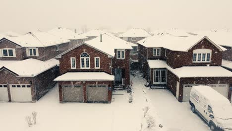 Private-Canadian-home-estates-during-heavy-snowfall,-aerial-drone-ascend-view