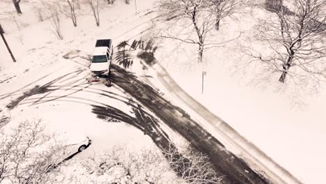 White-pickup-truck-plowing-local-streets-in-Toronto,-aerial-view-during-snowfall