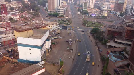 Yaoundé-downtown-traffic-with-many-yellow-taxis-circling-roundabout,-Aerial-dolly-in-view