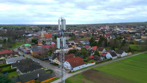 Flying-By-Cell-Tower-And-Houses-In-The-Neighborhood-At-Daytime-On-Rural-Field