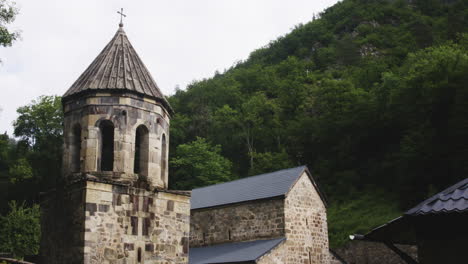 Bell-tower-and-church-of-Mtsvane-monastery-below-wooded-hill,-Georgia