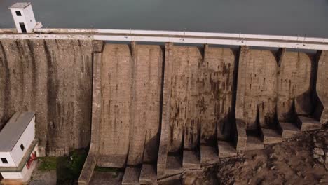 Establish-aerial-of-Tratalias-Dam,-tilt-down-and-up-reveals-beautiful-lake,-day