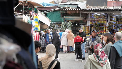 Moroccan-locals-walking-along-a-busy-street-of-stalls-in-Marrakesh-at-day-time-in-slow-motion