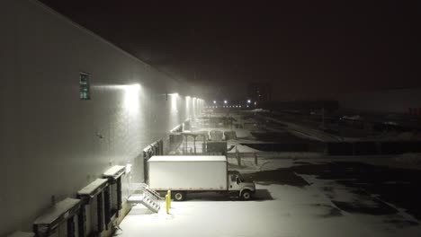 Luftflug-Neben-Einem-Modernen-Logistikzentrum-In-Der-Nacht-An-Kalten-Winterabenden-über-Geparkten-LKW-Und-Draußen-Gelassene-Waren