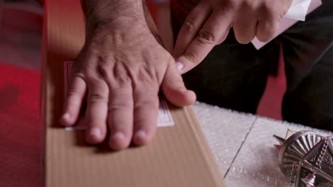 Hands-Sticking-Waybill-Onto-Cardboard-Box-For-Shipping
