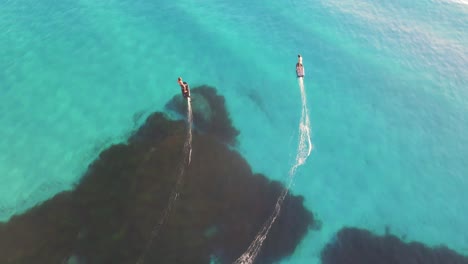Drone-footage-follows-two-people-surfing-the-crystal-clear-and-azure-waters-of-an-ocean-on-a-fliteboard