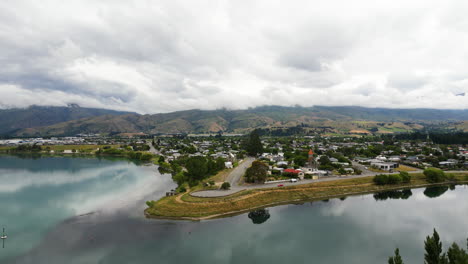 Beautiful-aerial-drone-shot-over-Cromwell-town-along-the-Dunstan-lake-in-New-Zealand-on-cloudy-day-with-the-view-of-mountain-range-in-the-background