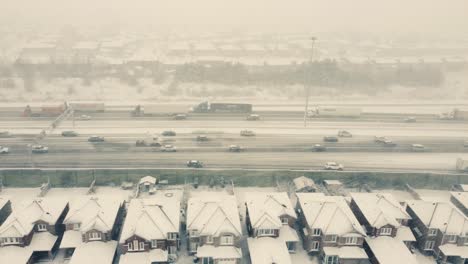 Aerial-over-busy-highway,-snowstorm,-middle-class-houses