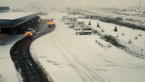 Heavy-snow-plow-truck-cleaning-private-industrial-area-during-snowfall,-aerial-view