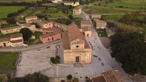Establisher-aerial-view-of-Tratalias-Church-and-square,-Sardinia,-lowering,-day