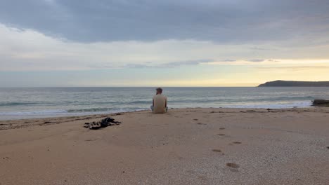 Ein-Mann-Sitzt-Am-Ufer-Eines-Wunderschönen-Strandes-An-Der-Australischen-Küste-Und-Blickt-Auf-Das-Meer-Und-Den-Sonnenuntergang