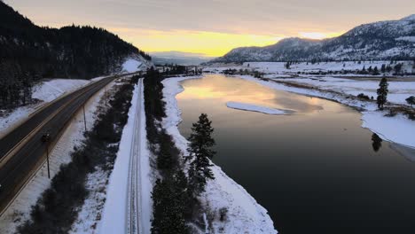Sunset-over-the-Thompson-River-and-Highway-1-in-Kamloops,-BC,-with-Snowy-Mountains-in-the-Background