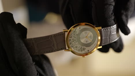 VERTICAL-gloved-hands-showcase-gold-clockwork-dial-Piaget-wristwatch-in-designer-retail-store,-Close-up