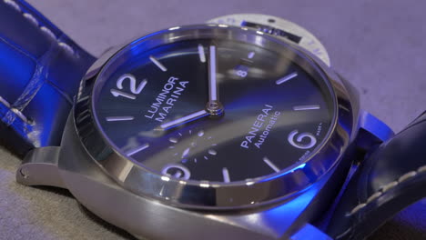 Stilvolle-Silberne-Maritime-Armbanduhr-Von-Panerai-Mit-Blauer-Beleuchtung,-Die-über-Das-Zifferblatt-Scheint,-Nahaufnahme