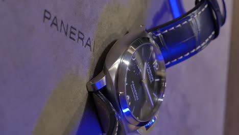 VERTICAL-Stylish-Panerai-wristwatch-with-blue-lighting-shining-across-dial,-close-up-in-retail-boutique