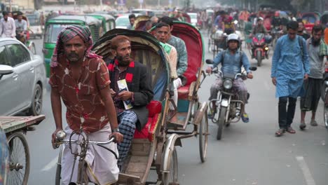 Filmaufnahme-Von-Bangladeschischen-Pendlern,-Die-Mit-Anderen-Fahrzeugen-Auf-Rikschas-Auf-Einer-Stark-Befahrenen-Straße-Fahren