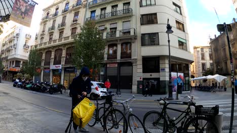 Glovo-Fahrradkurier-Mit-Gesichtsmaske-Kommt-Im-Starbucks-Restaurant-An,-Um-Die-Essensbestellung-Zur-Lieferung-Abzuholen-–-Valencia,-Spanien