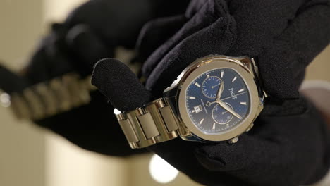 VERTICAL-Gloved-hands-showcase-luxurious-Piaget-brand-wristwatch-in-designer-retail-store-close-up