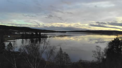 Drohne-Steigt-Bei-Sonnenuntergang-über-Bäumen-An-Einem-See-In-Schweden-Auf