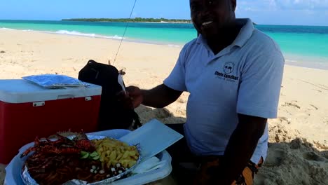 Local-tanzanian-tourist-guide-enjoying-seafood-platter-by-beautiful-beach,-Zanzibar