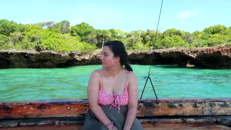 Caucasian-woman-sitting-in-a-wooden-boat-on-a-sea-safari-in-Africa's-blue-lagoon