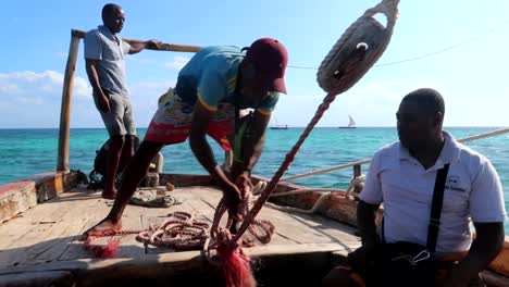 Tripulación-De-Marineros-Africanos-Arreglando-Una-Cuerda-En-Un-Barco,-Navegando-En-El-Océano-índico
