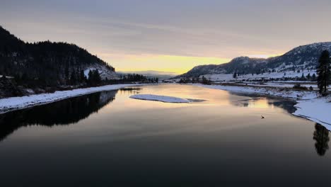 Thompson-River-during-sunset-in-winter-month,-Mountains-surrounding-Kamloops-British-Columbia-,-drone-shot