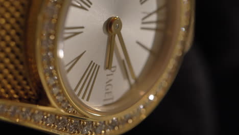 VERTICAL-panning-shot-across-expensive-Piaget-gold-wristwatch-set-with-sparkling-diamonds-around-dial,-close-up