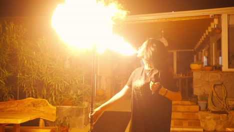 Young-Female-Fire-Blower-Fire-eater-Blowing-Gasoline-on-Torch-Making-Big-Flames,-Slow-Motion